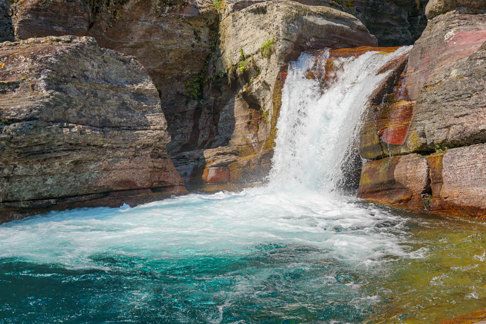 young man sitting on a rock beside a waterfall
